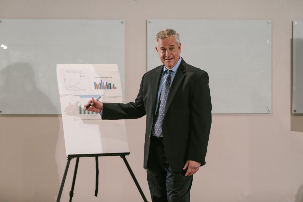 a man in black suit discussing in front